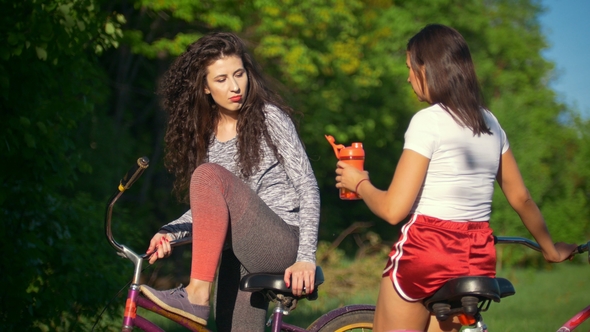 Two Female Cyclists Drink Water and Talk on Sunny Summer Day