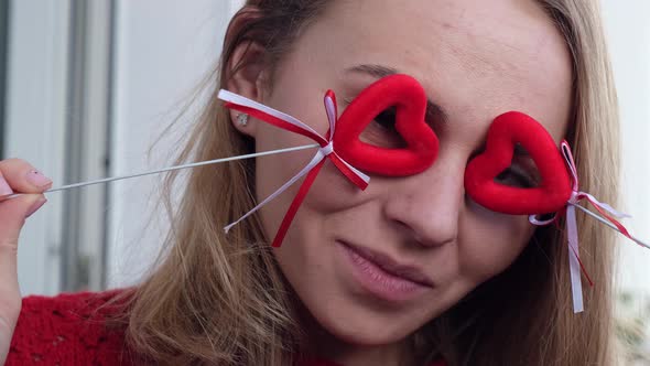 Young Blonde Girl in Red Sweater Holding Red Hearts Showing Emotions