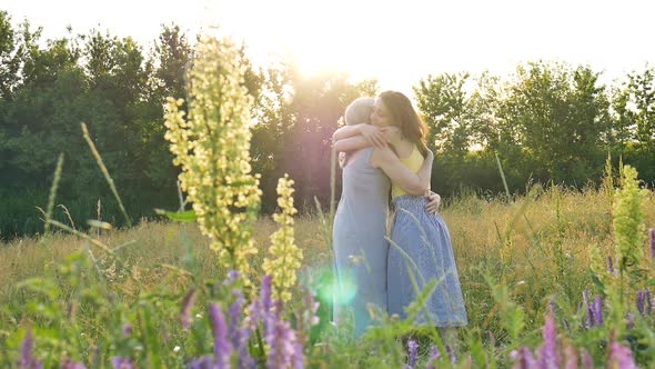 Back View of Senior Mother with Gray Hair with Her Adult Daughter in the Garden Hugging Each Other