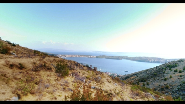 Aerial Footage Soaring Over Mountain Range and Descending To Coastal Village