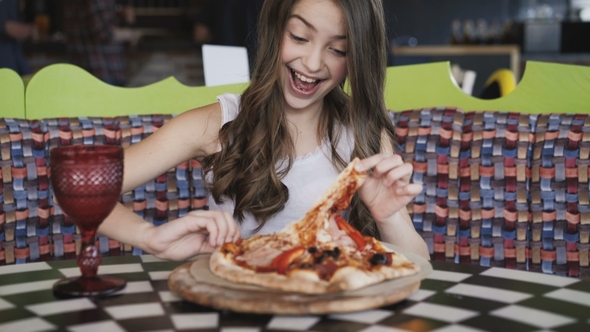 Pretty Young Girl Eating Pizza with Enjoy in Café