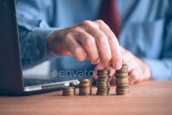 inessman with stacked money coins on office desk