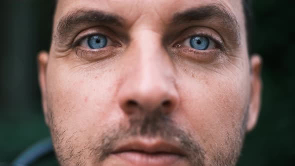 Closeup Face of a Young Man with Bright Blue Eyes Looking Seriously with Curiosity