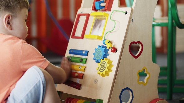 A Little Boy in a Kindergarten Plays a Developing Toy