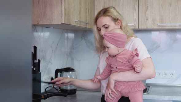 Mother Prepares Food Holding Baby in Her Arms