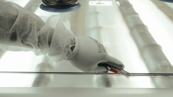 Worker Hand Using Knife for Cutting Matting Film From Glass in Industrial Pant