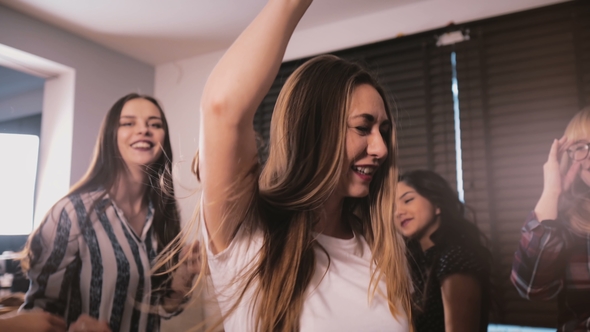 Beautiful Happy European Girl Dancing and Smiling at a Casual House Party with Multiethnic Friends