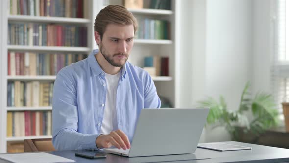Man Celebrating Success While Using Laptop in Office