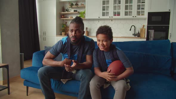 Joyful African American Boy with Father Celebrating First Down with Football
