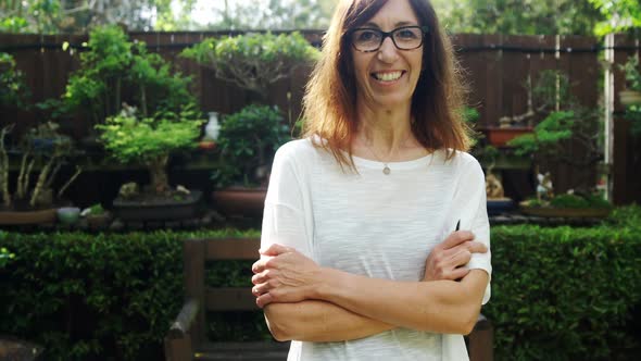 Mature woman standing with arms crossed in the garden