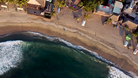 Top-down aerial passive drone shot of Sayulita beach in Mexico during golden sunset hours.