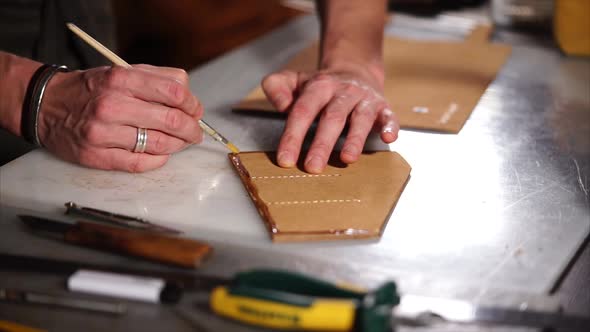 Close Up Shot of Master Hands, Who Smears the Piece of Leather in the Workshop