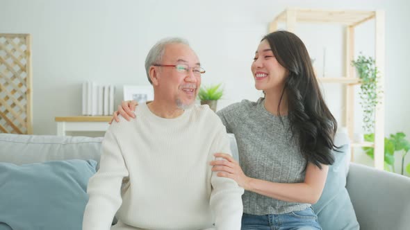 Portrait of Asian daughter visit older father and watch movie together.