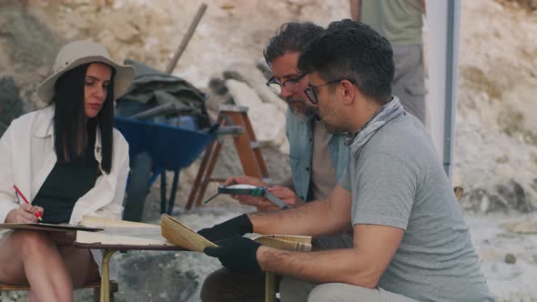 Male and Female Archaeologists Examining Maps Together