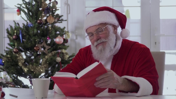 Santa Claus Is Drinking From a Cup and Reading a Book