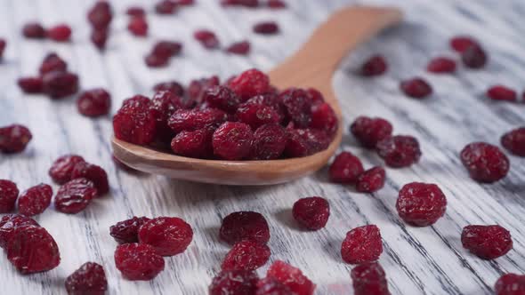 Dried red cranberries in a wooden spoon and sprinkled on an old texture table. 