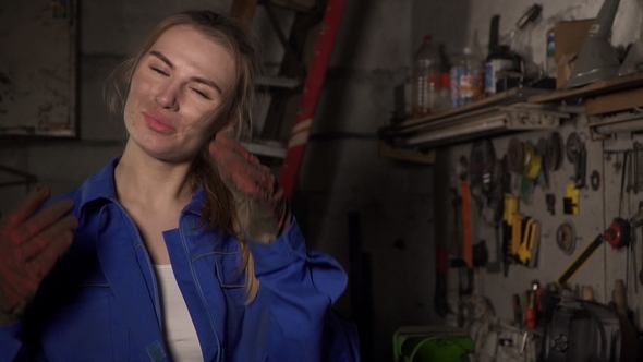 Cute Girl Mechanic in a Garage on the Background of the Instruments Smiling