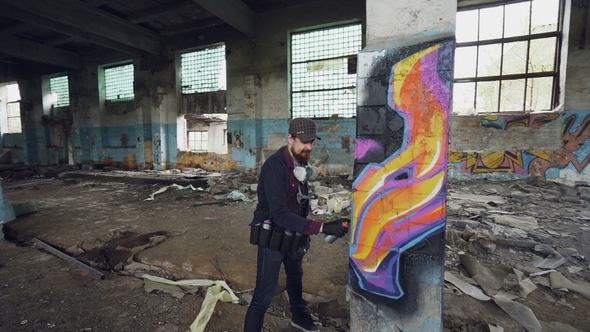 Pan Shot of Damaged Abandoned Building with High Columns Inside and Male Graffiti Artist Drawing