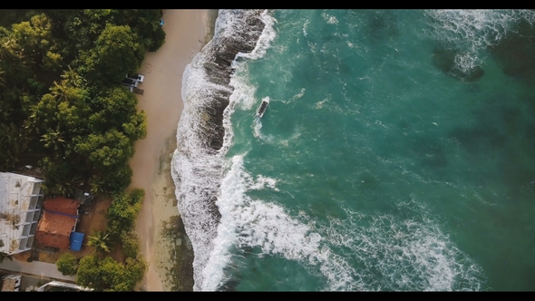 Aerial Flyover Drone Shot of Idyllic Exotic Sea Shore with Little Boat, Foaming White Crashing Waves