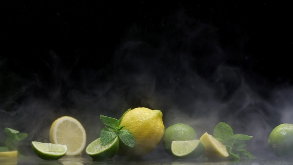 Tropical Lemon Lime Cuts in Cold Ice Clouds of Fog Under Water Spray Droplets Black Background