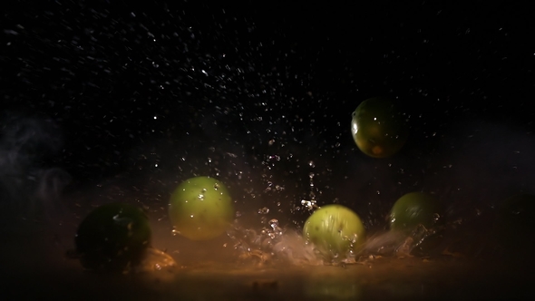Lime Fruits Falling on Water Surface in Orange Light Spot and Cloud of Fog