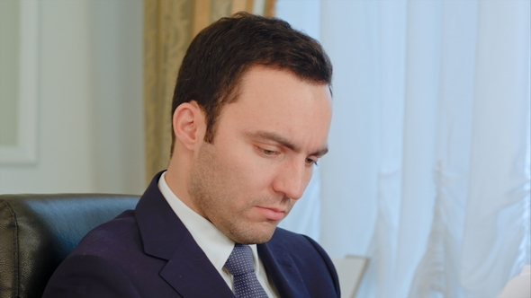 Young Businessman Signing Documents in the Office