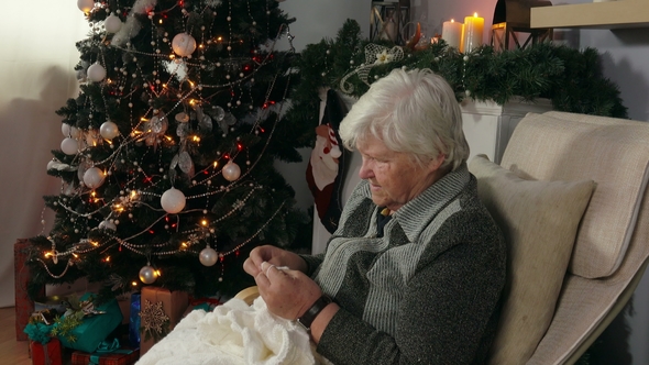 Elderly Woman Knits a Blanket Sitting in a Chair