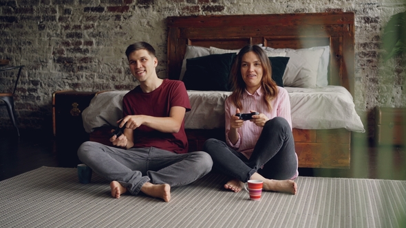 Young Couple Boyfriend and Girlfriend Are Playing Video Game Holding Joysticks