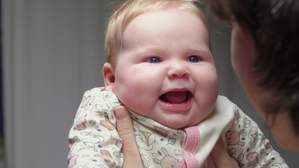 Cute Blue-eyed Kid Smiling at Mom's Arms