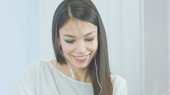 Happy Young Woman Inserting Earphones Into Her Ears and Enjoying Music