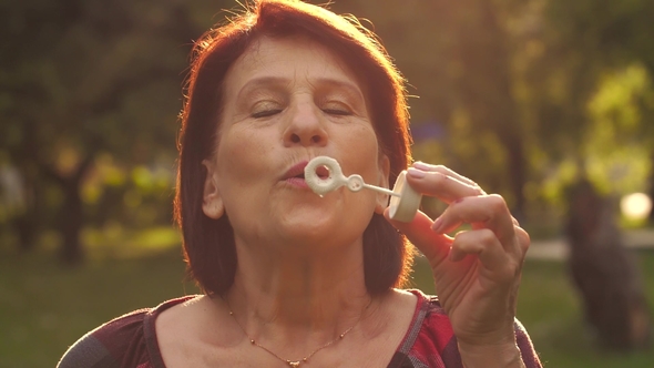 Mature Woman Blowing Soap Bubbles