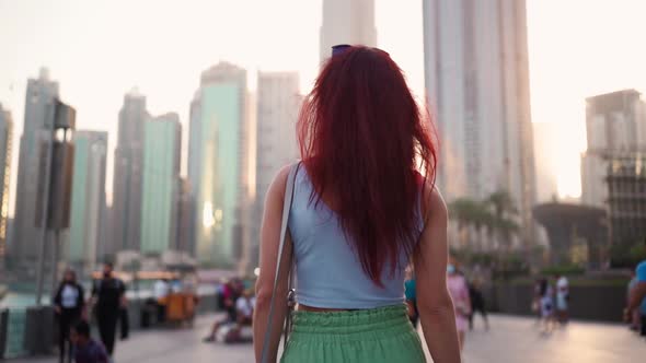 View From the Back a Woman with Red Hair is Walking in the Center of Dubai