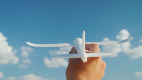 A Male Hand Holds a Toy Airplane Directed To the Sky. Idea and Dream in Business Concept