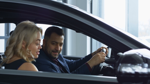 Successful Couple Testing New Car in Salon