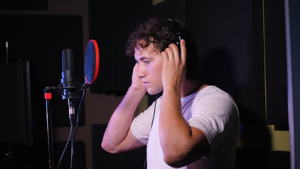 Young Handsome Singer Man Puts on Headphones in the Studio. Recording New Melody or Album