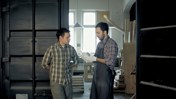 Two Woodworkers in Factory Discussing in About Something