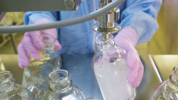 Worker Pours Liquid Into Capacites in Chemical Laboratory