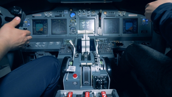 Two Men Are Sitting in a Cockpit of a Flight Simulator and Are Operating a Flight