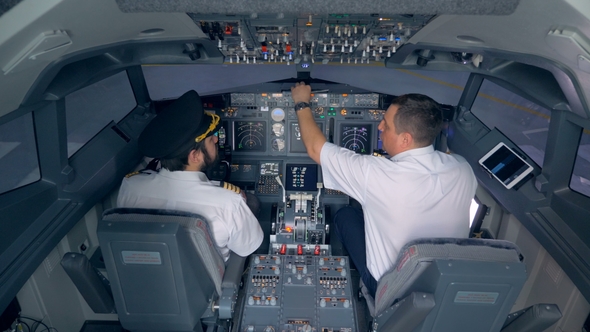 Two Pilots Are Sitting in an Airplane Cabin and Discussing Something