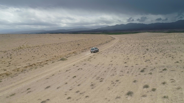Suv Car Goes on Sandy Wasteland. Desert Landscape. Aerial Low Angle View