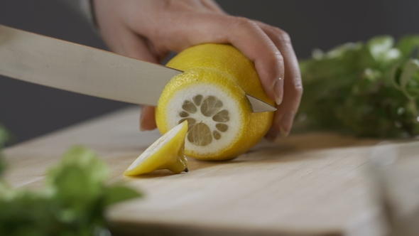 Someone Cutting a Lemon on the Chopping Board