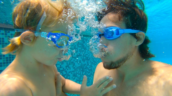 Underwater Shot of Father and His Toddler Son Swining Diving and Having Fun in a Pool