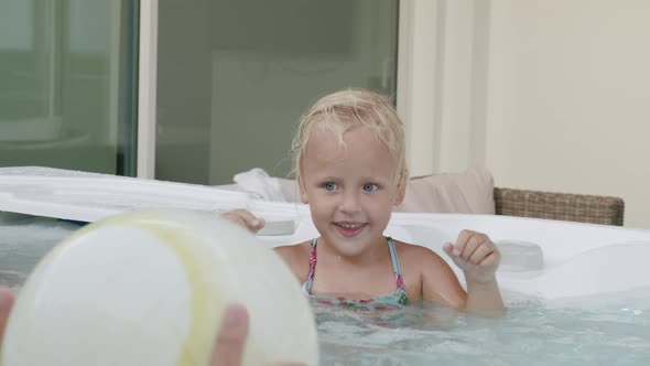 Little girl enjoying fun day with family bathing in hot tub