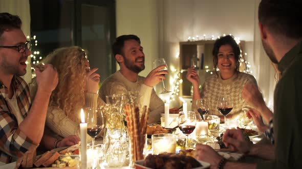 Happy Friends Drinking Red Wine at Christmas Party