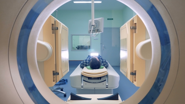 Medical Scanning Equipment and a Male Patient. Man Lays in Magnetic Resonance Image Device