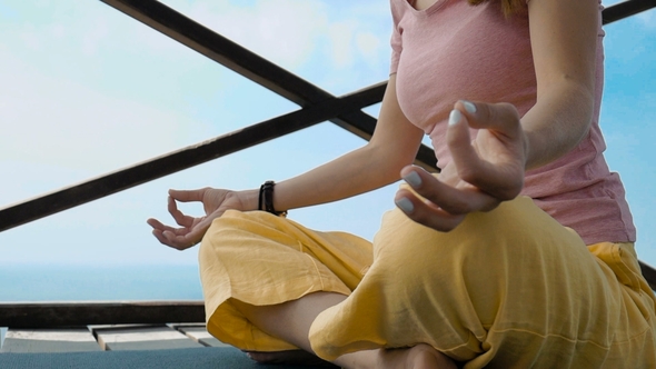 Young Woman Doing Yoga in a Small House on Top of a Cliff