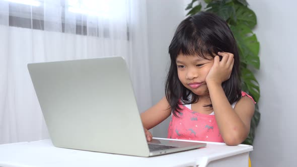 Funny Asian child learning class study online with a video calls from a notebook