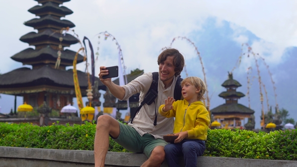 Father and Son Taking Selfie in Front of a Pura Ulun Danu Temple on the Lake Bratan in Bali