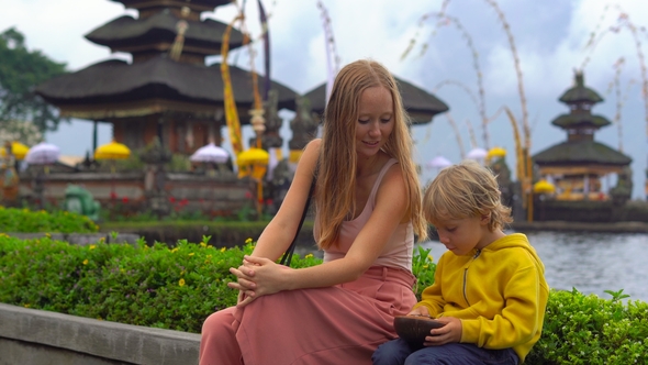 Young Woman and Her Son Sitting in Front of a Pura Ulun Danu Temple on the Lake Bratan in Bali