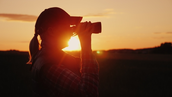 A Woman Looking Through Binoculars at Sunset. Travel and Safari Concept